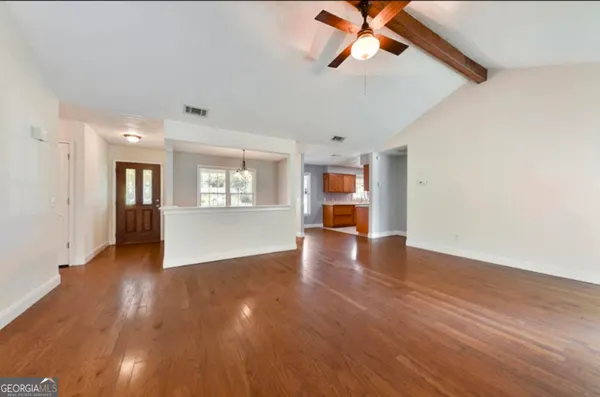 a view of an empty room with wooden floor and a window