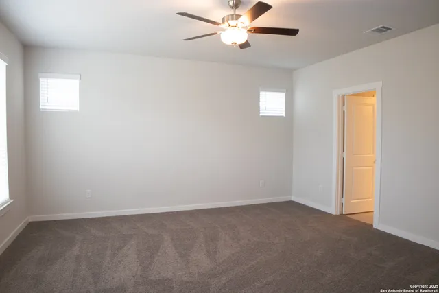 an empty room with windows and fan