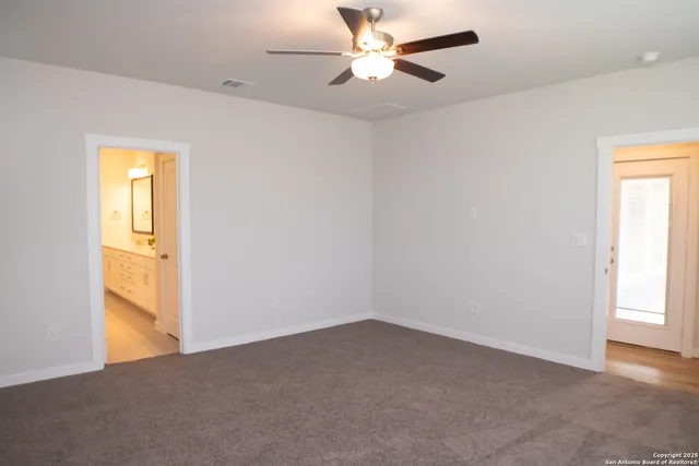 an empty room with a window and a ceiling fan