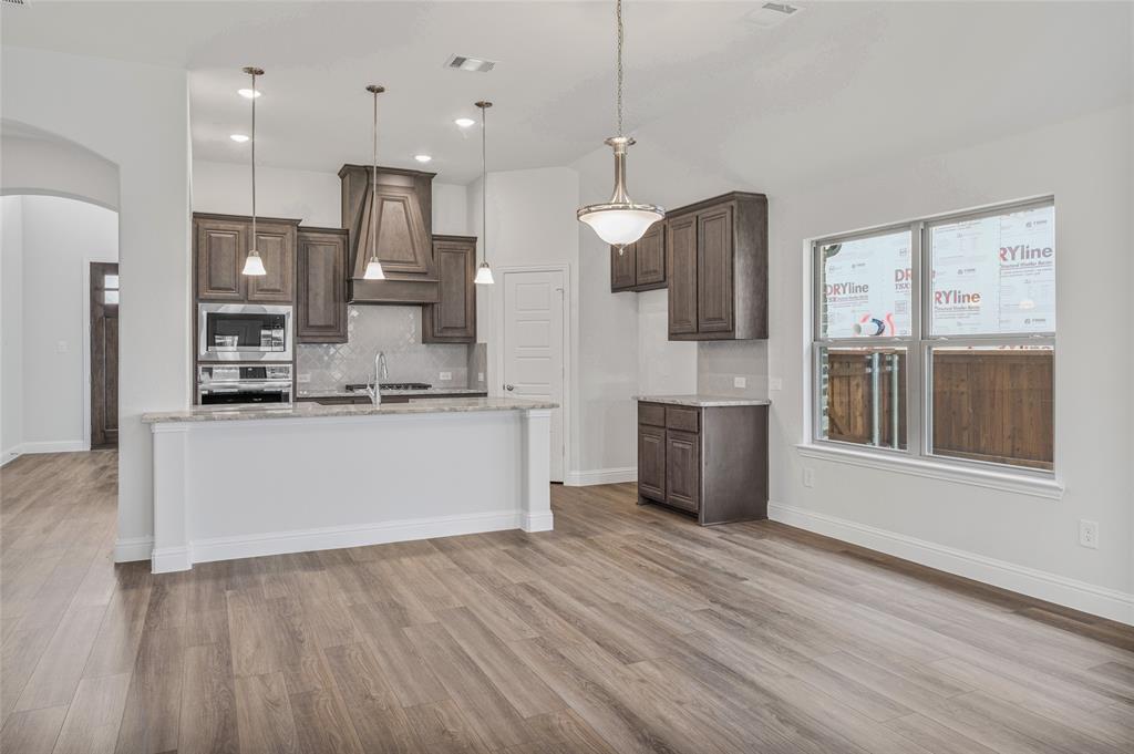 14566 Helena Street Pilot Point, TX 76258 - Photo 16 of 37 a large kitchen with stainless steel appliances kitchen island a large counter top and wooden floors