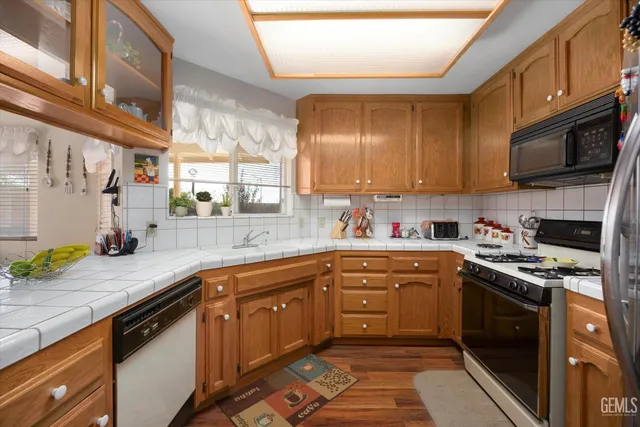 a kitchen with stainless steel appliances granite countertop a sink a stove top oven a counter space and cabinets