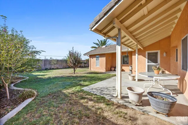 a view of a patio with table and chairs potted plants and wooden fence