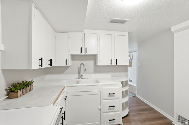270 East 700 North Logan, UT 84321 - Photo 22 of 42 Kitchen featuring white cabinetry, white countertops, a double basin sink with a gooseneck faucet, and wood-finish flooring