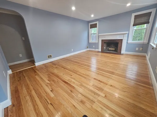 a view of empty room with wooden floor and fireplace