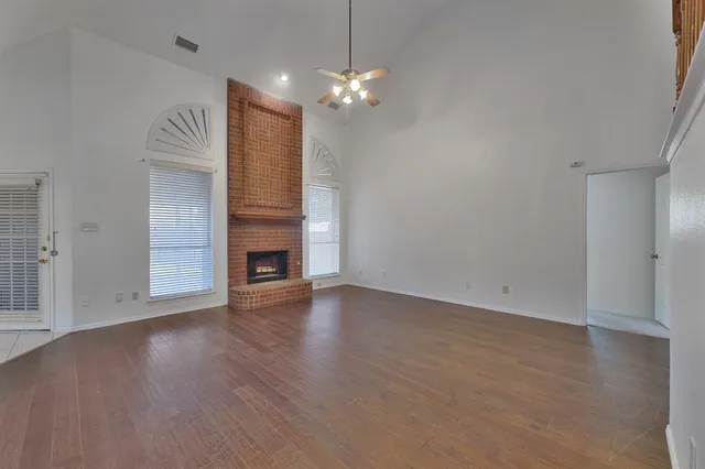 a view of an empty room with wooden floor and a fireplace