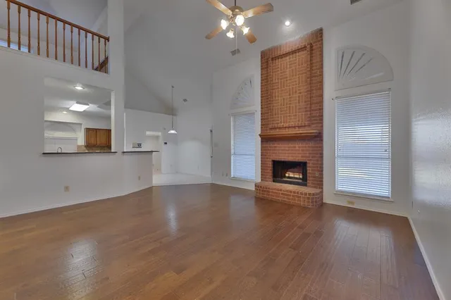 a view of an empty room with wooden floor and a fireplace