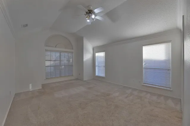 an empty room with windows and ceiling fan