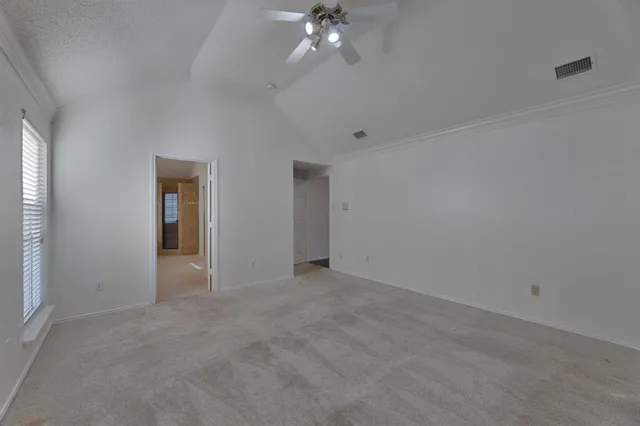 an empty room with chandelier fan and windows