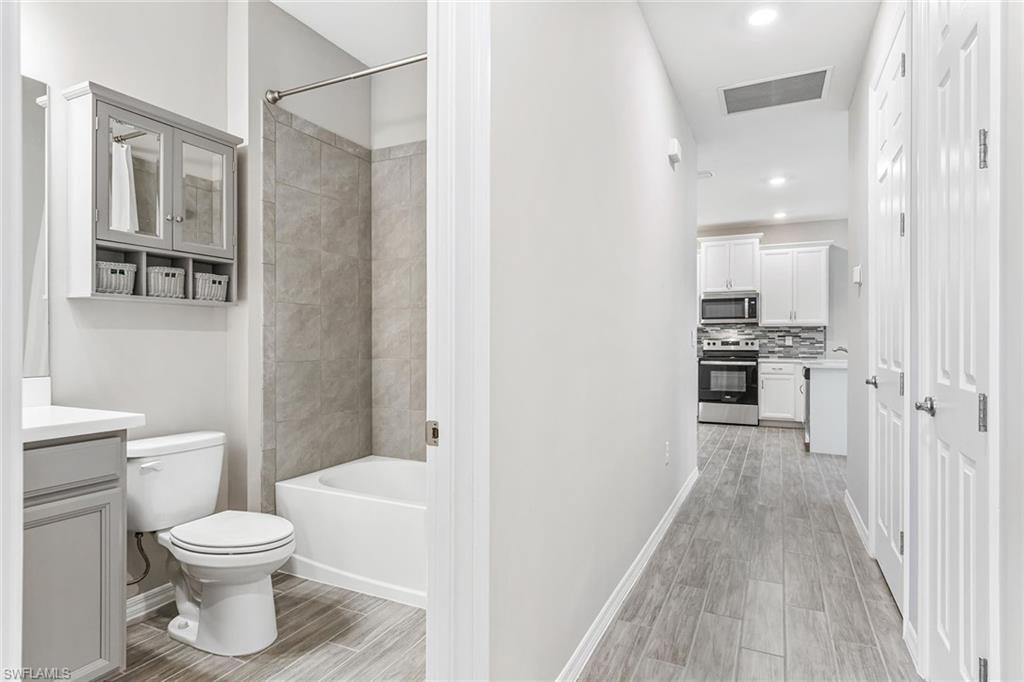 1252 Enbrook Loop Naples, FL 34114 - Photo 16 of 26 a bathroom with a toilet a sink and a wooden floor