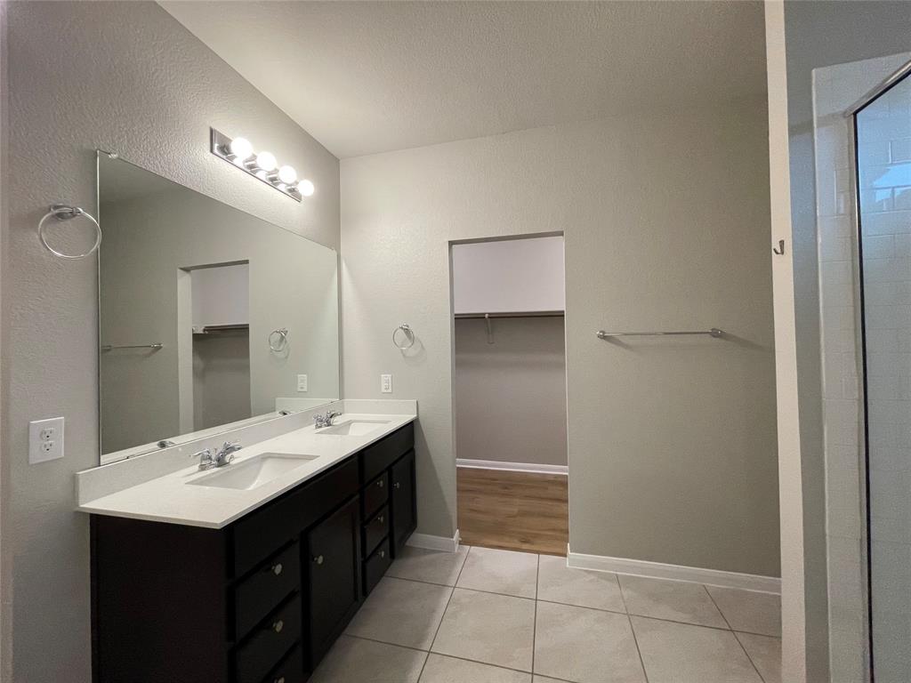 6717 Ranchito Drive Austin, TX 78744 - Photo 13 of 28 The primary bedroom's ensuite features a dual vanity with under-mount sinks, plenty or storage, and a standing shower.
