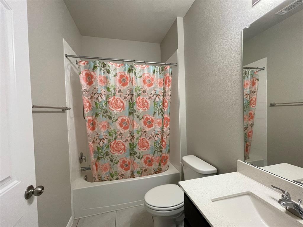 6717 Ranchito Drive Austin, TX 78744 - Photo 18 of 28 Bathroom featuring a textured wall, shower / bath combination with curtain, vanity, and tile patterned flooring