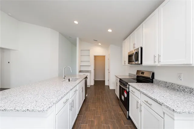 a large kitchen with stainless steel appliances granite countertop a lot of counter space and wooden floors