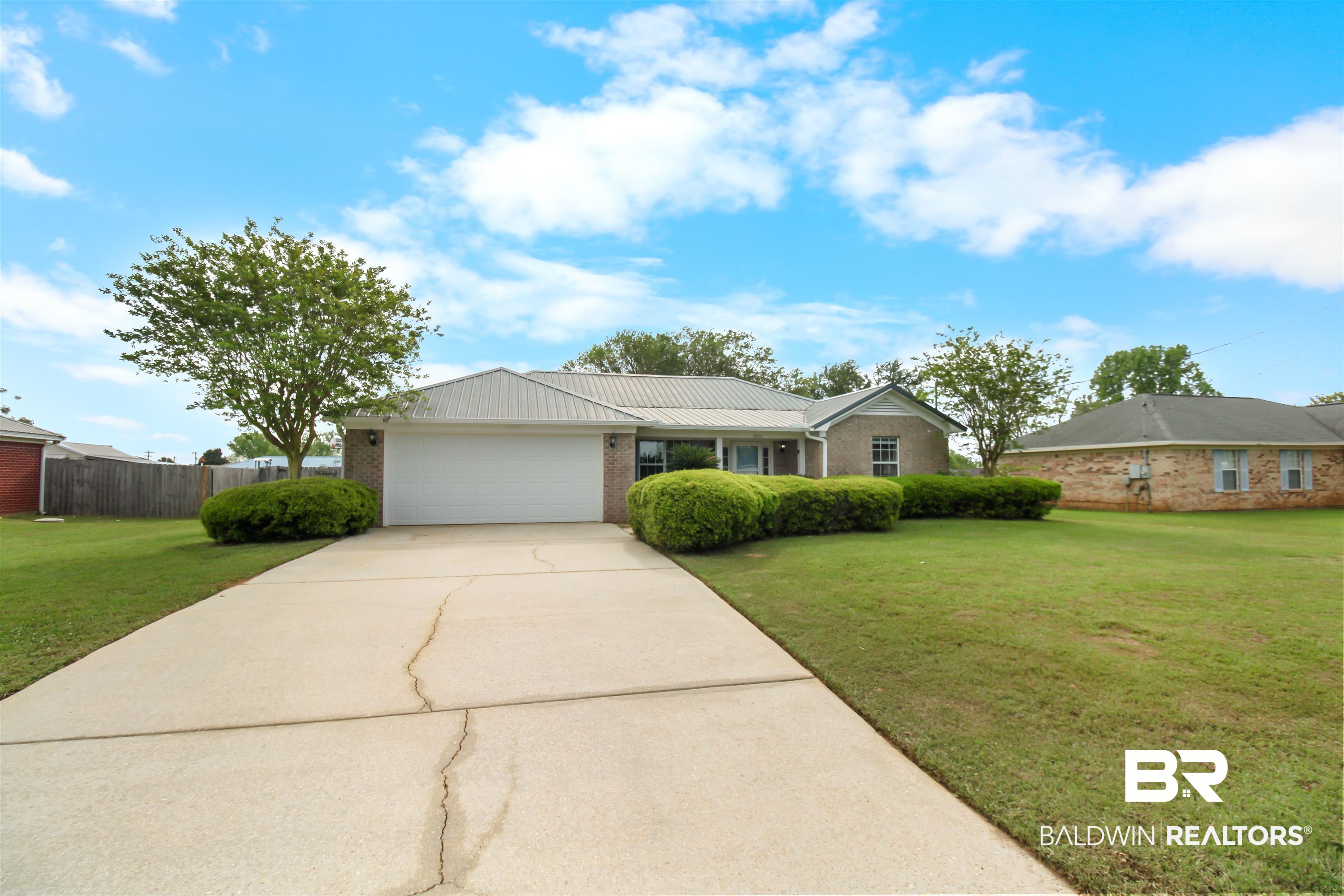 8940 Caitlin Street Foley, AL 36535 - Photo 23 of 27 Ranch-style house featuring a garage, brick siding, driveway, and a metal roof