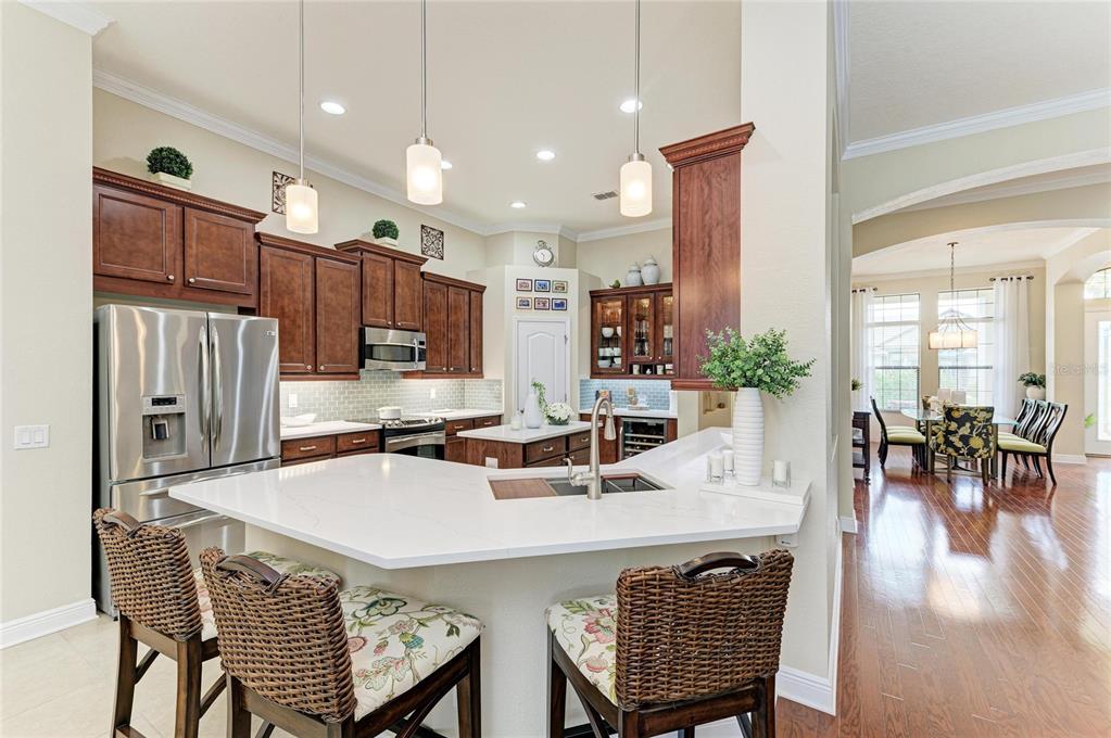 302 Cockle Shell Loop Apollo Beach, FL 33572 - Photo 26 of 75 an open kitchen with granite countertop a stove a sink a dining table and chairs