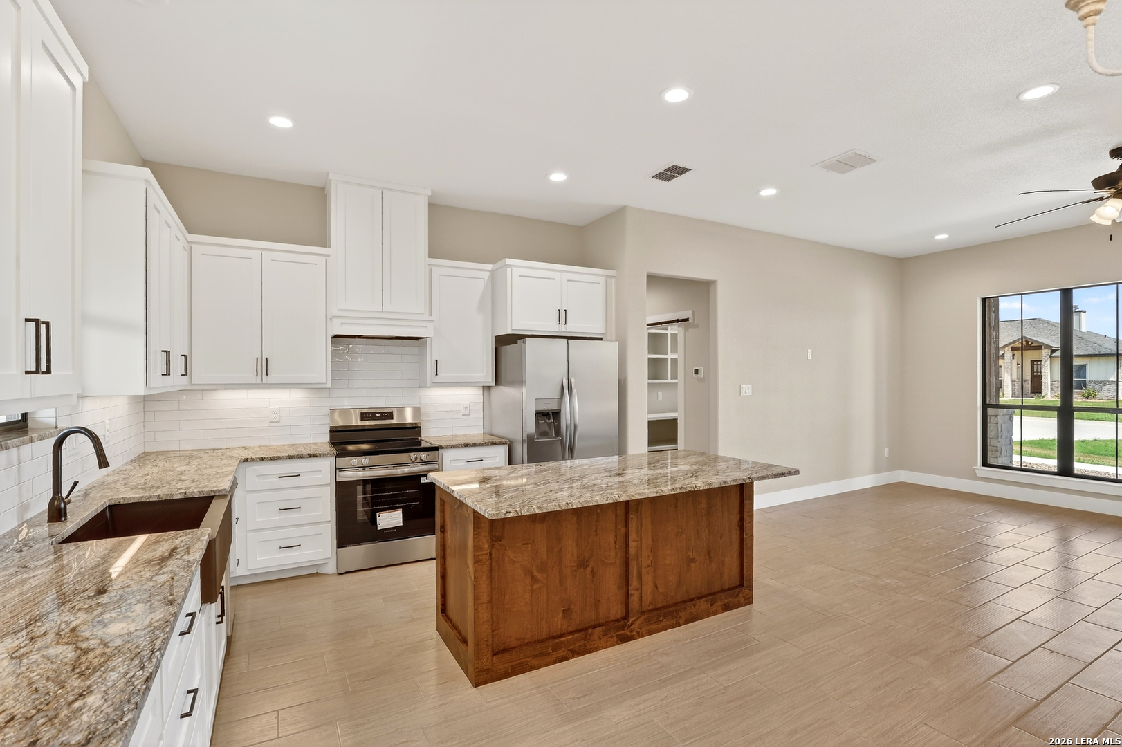 721 North Dickson Street Poth, TX 78147 - Photo 14 of 40 a large kitchen with stainless steel appliances granite countertop a stove a sink a refrigerator and white cabinets with wooden floor
