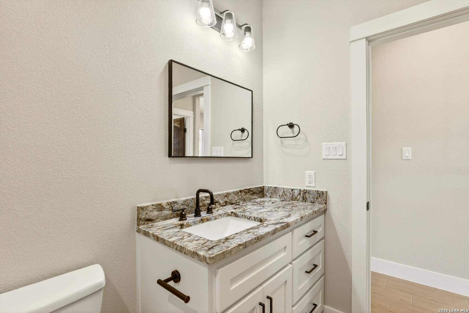 721 North Dickson Street Poth, TX 78147 - Photo 34 of 40 a bathroom with a granite countertop sink and a mirror