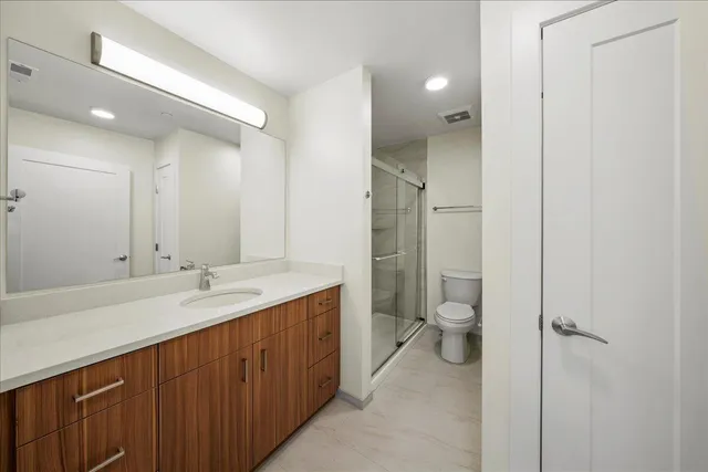 a spacious bathroom with a granite countertop toilet sink and mirror