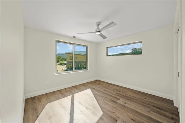 a view of a bedroom with wooden floor and windows