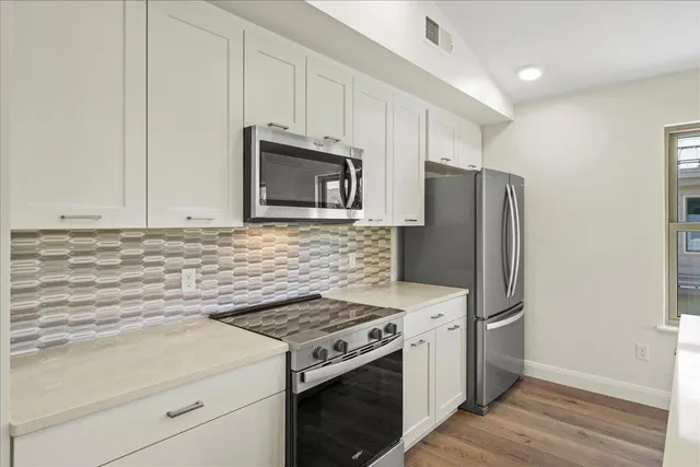 a kitchen with stainless steel appliances white cabinets and a stove top oven