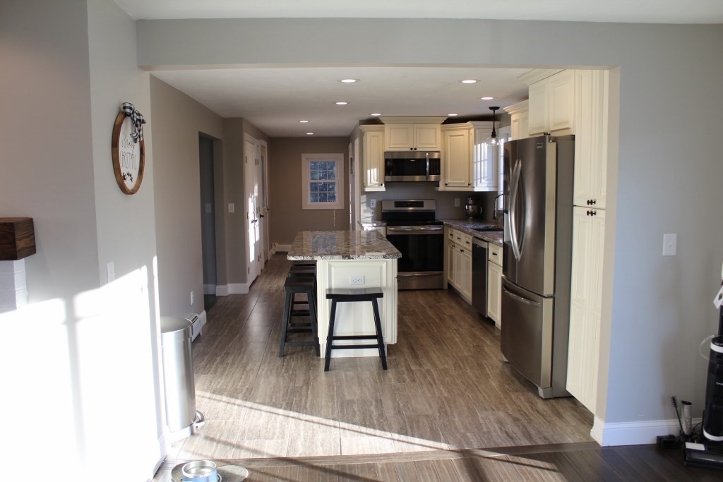 47 Old Coach Road Barre, MA 01005 - Photo 8 of 31 a kitchen with stainless steel appliances a refrigerator a stove top oven a sink dishwasher a dining table and chairs with wooden floor