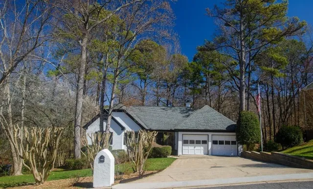 a front view of a house with a garden and trees