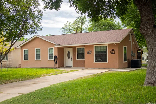 a view of a house with a yard and large tree