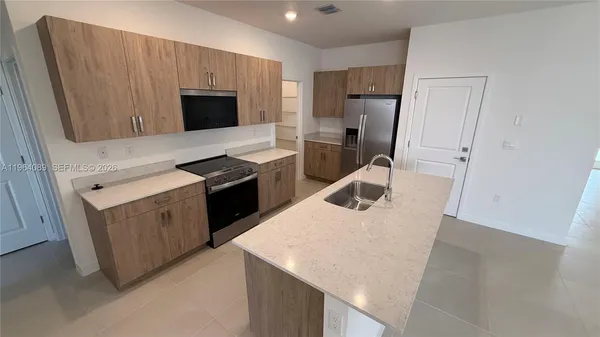 a kitchen with stainless steel appliances a refrigerator a sink a stove and cabinets