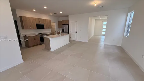 a large white kitchen with a sink a microwave and cabinets