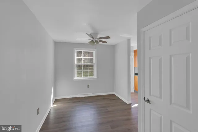 an empty room with wooden floor fan and windows