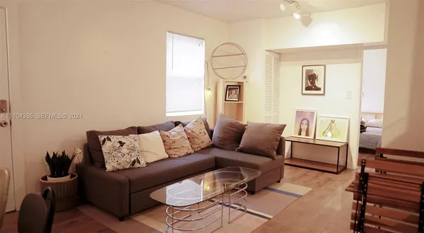 a living room with furniture kitchen view and large wooden floor
