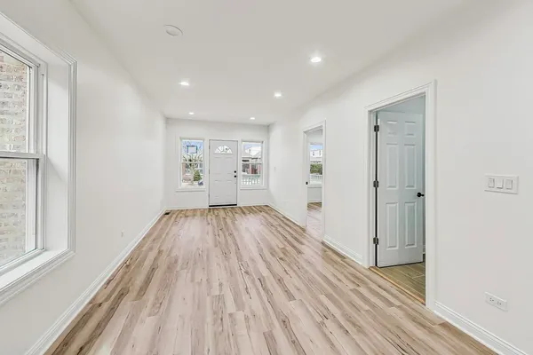 a view of empty room with wooden floor and fan