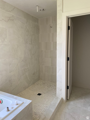 4676 West 75 North, Unit 401 West Point, UT 84015 - Photo 15 of 17 Tiled walk-in shower with a low-curb entry, featuring large format marble-look wall tiles and a hexagonal mosaic floor