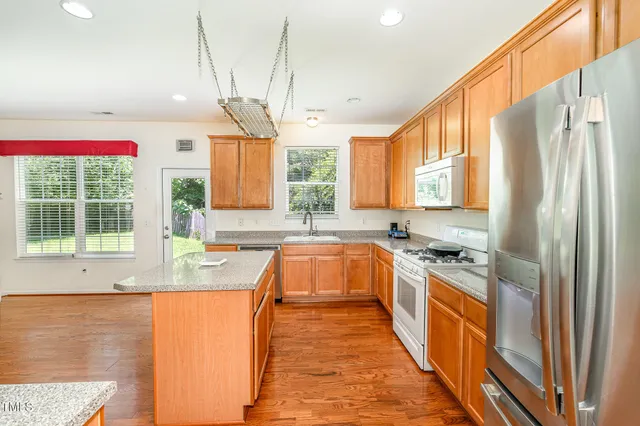 a kitchen with stainless steel appliances a refrigerator a sink dishwasher a stove with wooden floor and cabinets