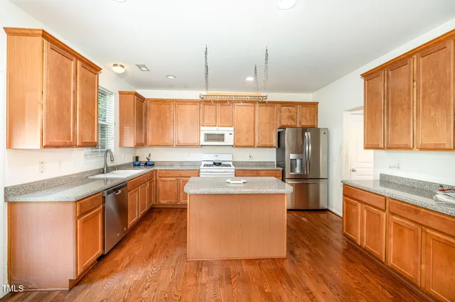 a kitchen with stainless steel appliances granite countertop a stove a sink dishwasher and a refrigerator with wooden floor