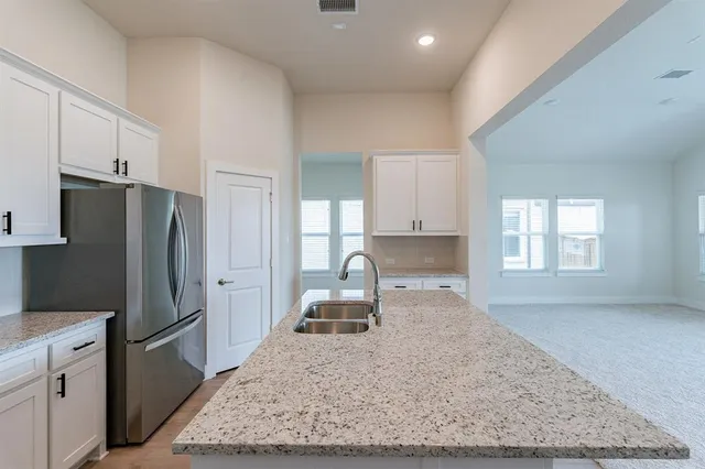 a kitchen with granite countertop a sink cabinets and wooden floor