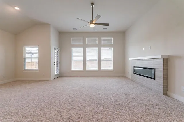 an empty room with windows and fireplace