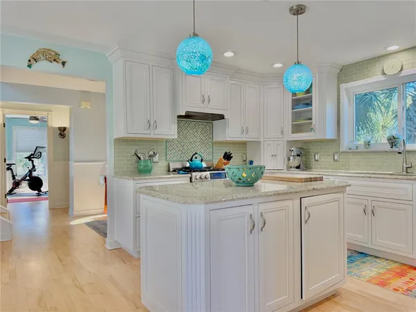 a kitchen with kitchen island granite countertop a sink a counter and a refrigerator