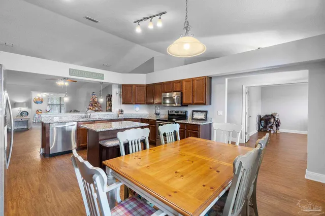 a kitchen with stainless steel appliances granite countertop a stove a sink dishwasher a microwave oven and a dining table with wooden cabinet