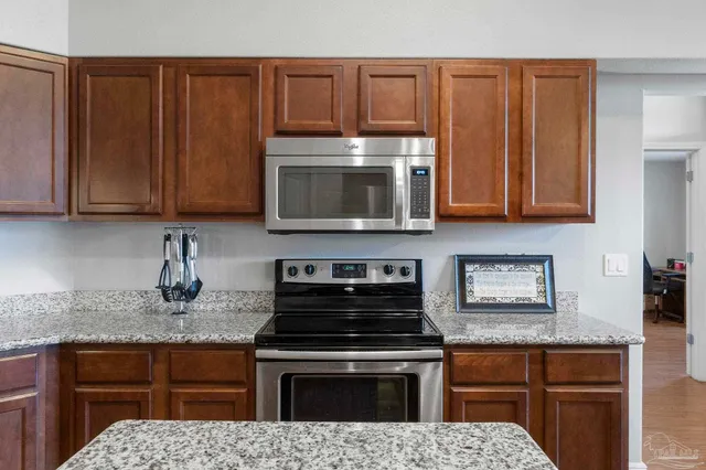a kitchen with granite countertop a sink a center island stainless steel appliances and cabinets