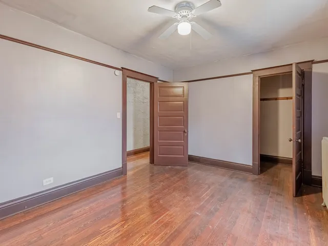 an empty room with wooden floor closet and windows
