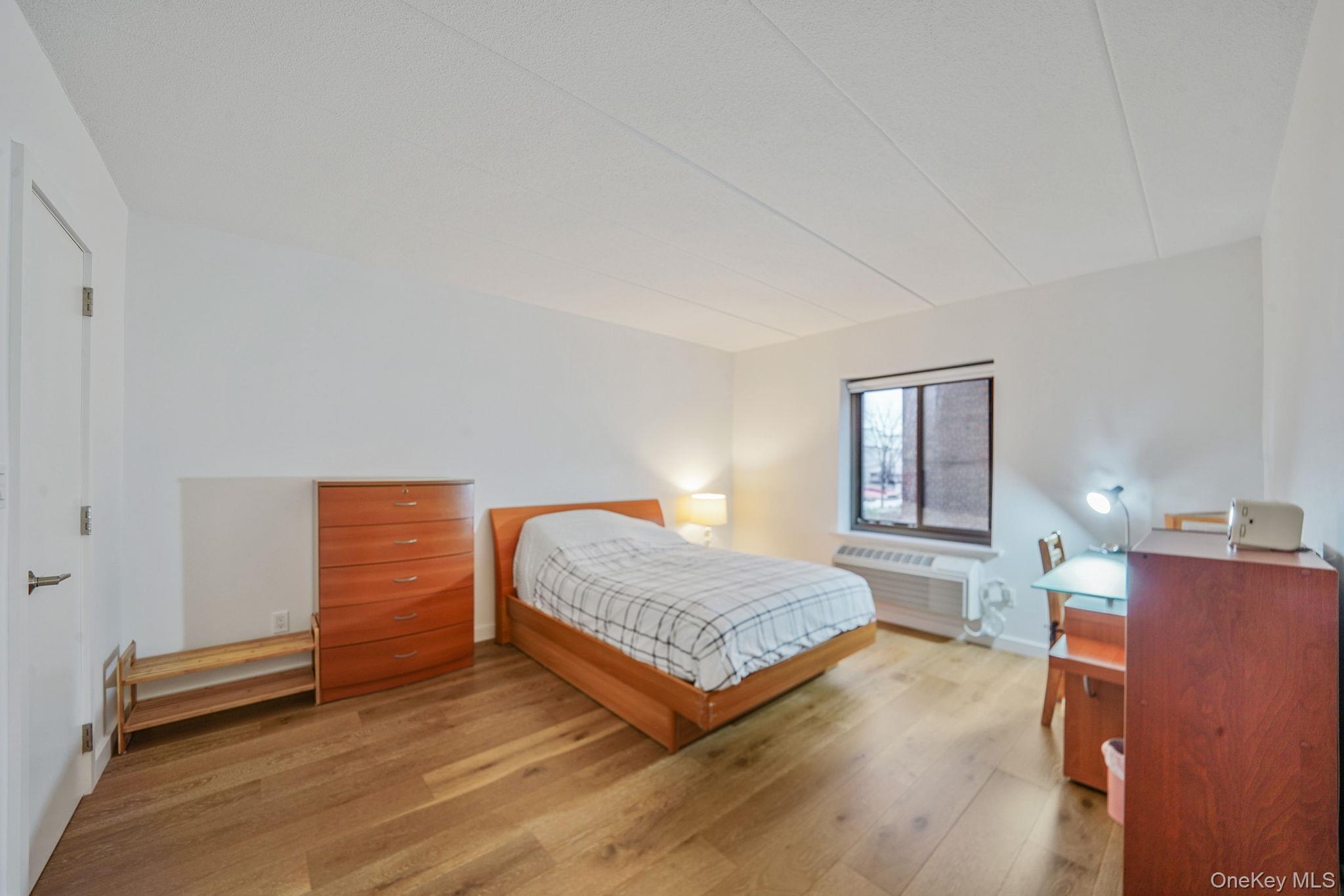 213-02 42nd Avenue, Unit 2A Queens, NY 11361 - Photo 15 of 24 a bedroom with a bed and dresser with mirror