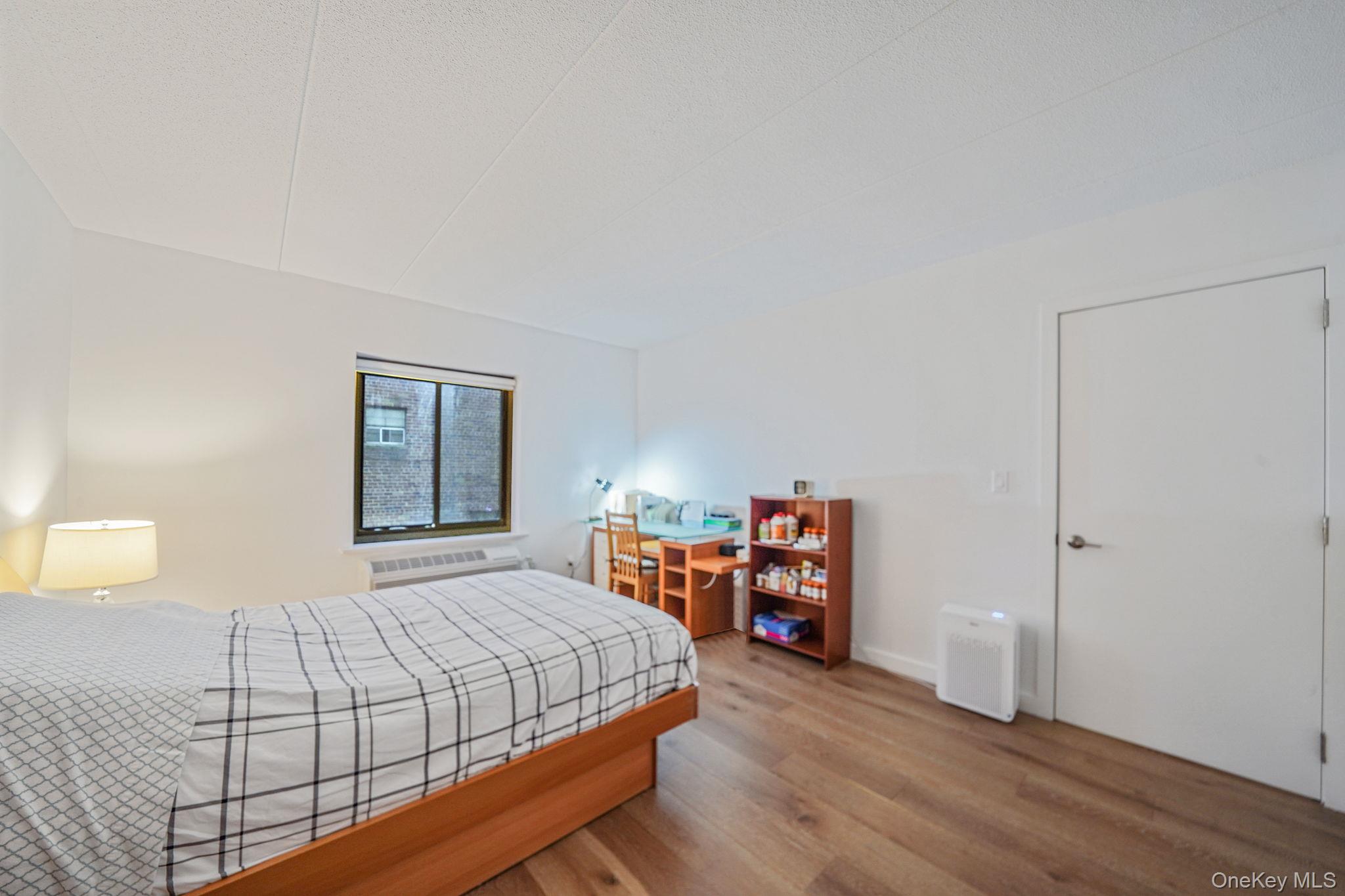 213-02 42nd Avenue, Unit 2A Queens, NY 11361 - Photo 17 of 24 a bedroom with a bed and a bookshelf