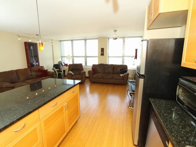 655 West Irving Park Road, Unit 4014 Chicago, IL 60613 - Photo 12 of 16 a living room with stainless steel appliances kitchen island granite countertop furniture and a large window
