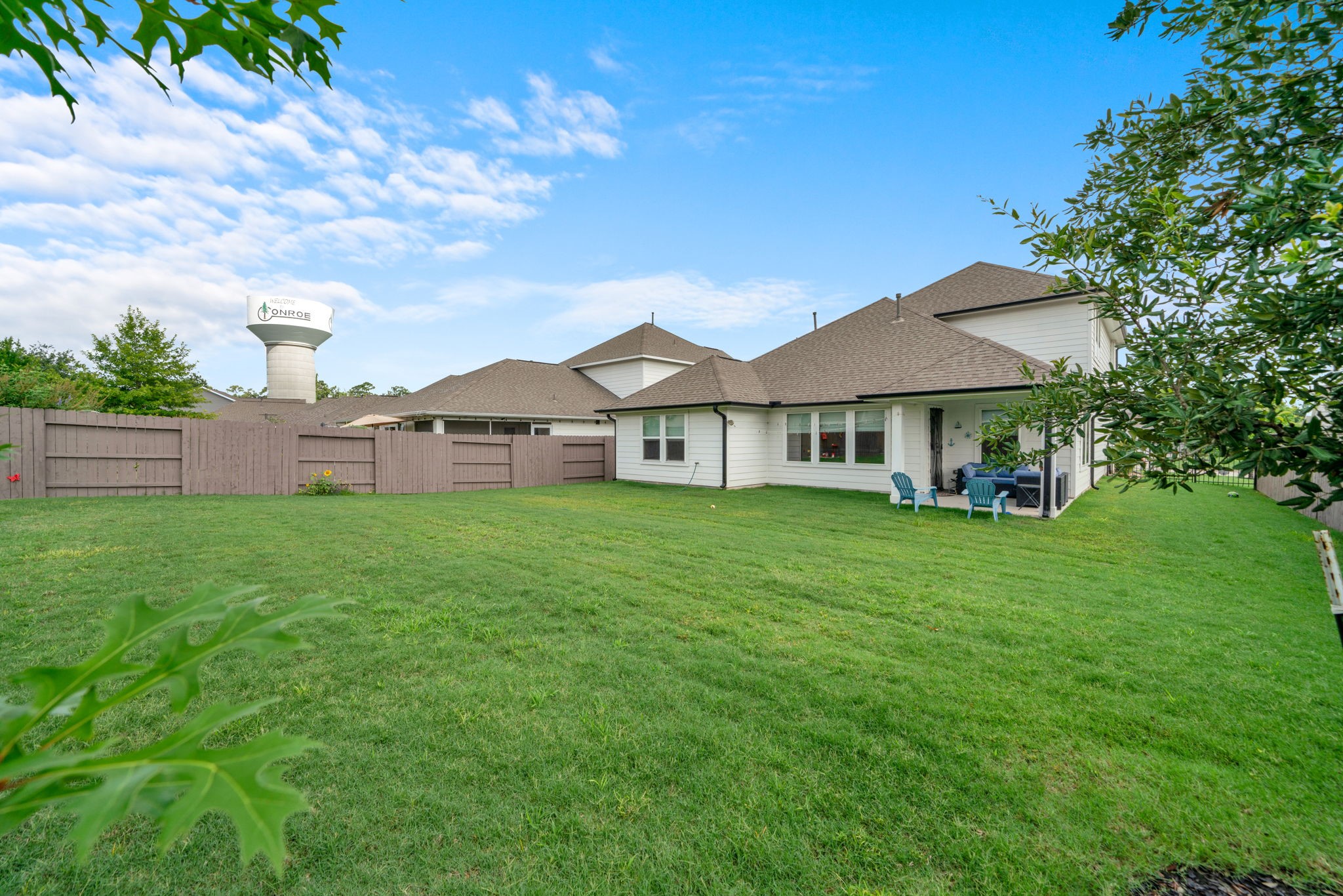2503 Hagerman Road Conroe, TX 77384 - Photo 5 of 43 Spacious backyard with lush green lawn, a cozy patio area, and a wooden fence for privacy. Ideal for outdoor activities and relaxation.