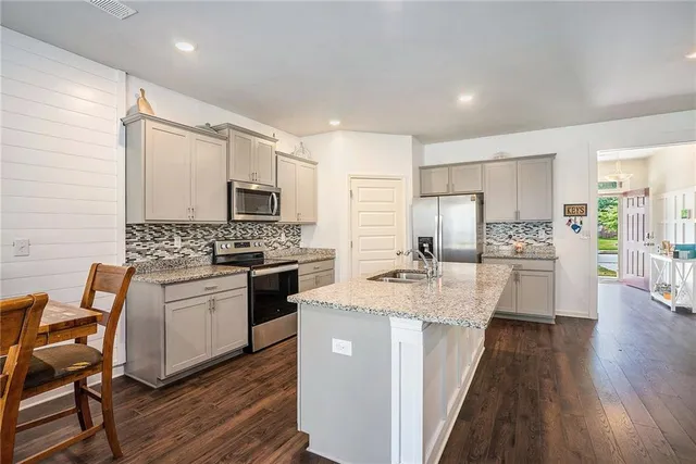 a kitchen with stainless steel appliances kitchen island granite countertop a stove refrigerator and cabinets