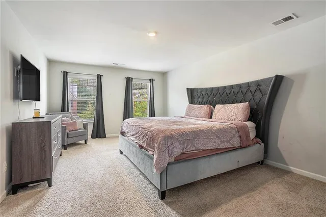 a spacious bedroom with a large bed and a flat tv screen on dresser