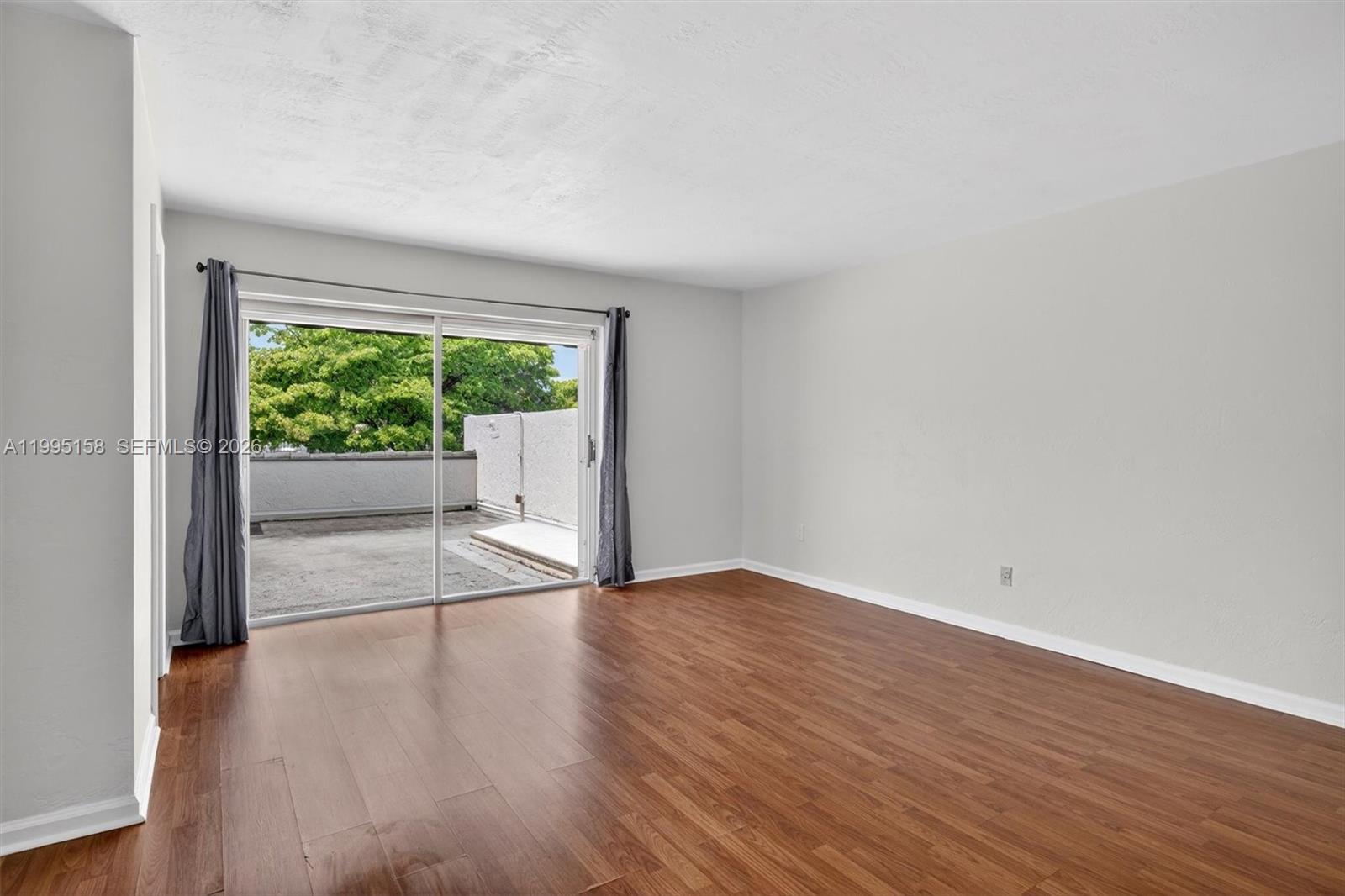 6161 Southwest 90th Court, Unit G2 Miami, FL 33173 - Photo 23 of 47 a view of an empty room with wooden floor and a window