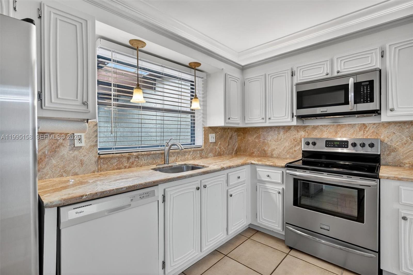 6161 Southwest 90th Court, Unit G2 Miami, FL 33173 - Photo 9 of 47 a kitchen with stainless steel appliances granite countertop white cabinets granite counter tops and a window