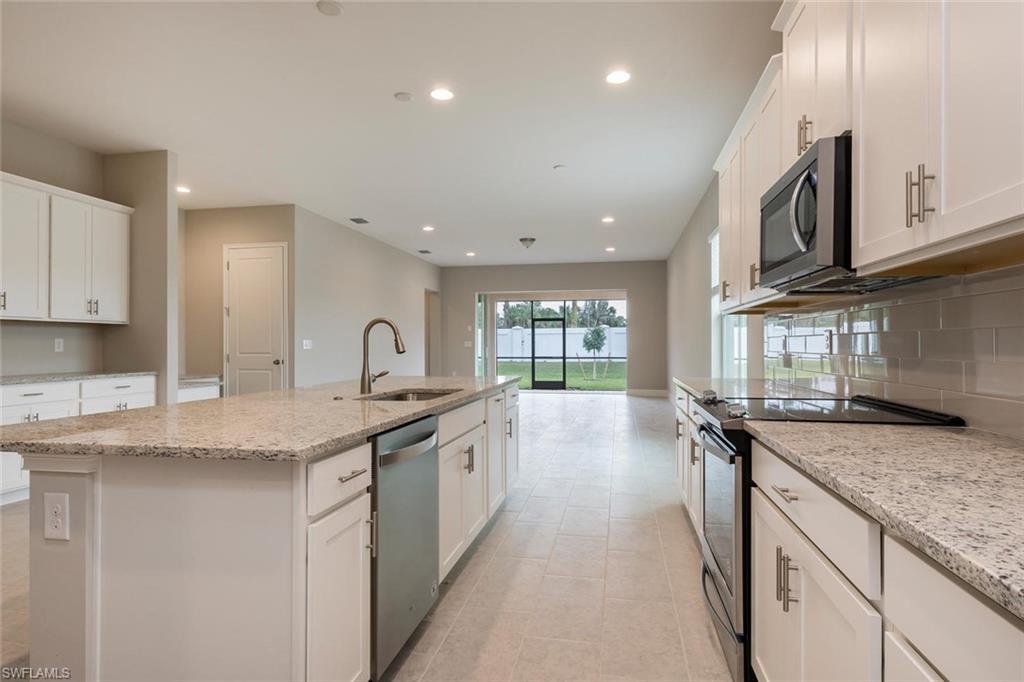 3509 Pilot Circle Naples, FL 34120 - Photo 11 of 32 a kitchen with granite countertop a sink stove and cabinets