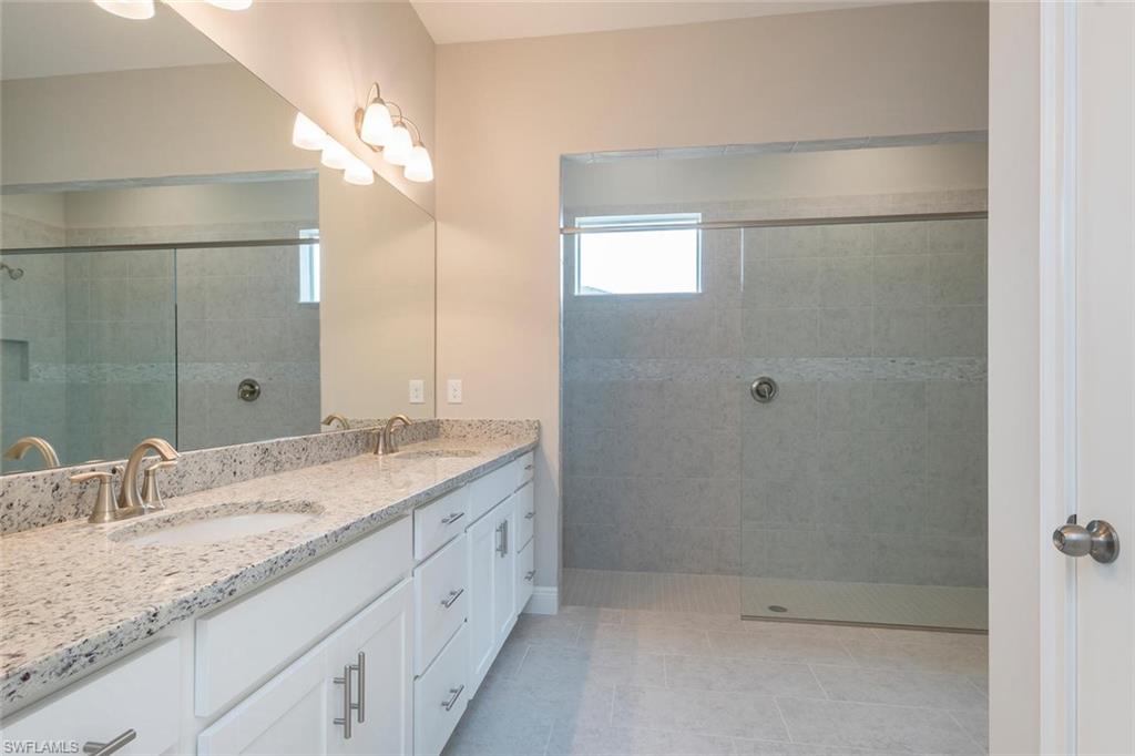 3509 Pilot Circle Naples, FL 34120 - Photo 18 of 32 a bathroom with a granite countertop sink a mirror and a shower